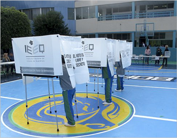 Se muestran 3 urnas colocadas en una escuela primaria, donde 3 niños están efectuando su voto